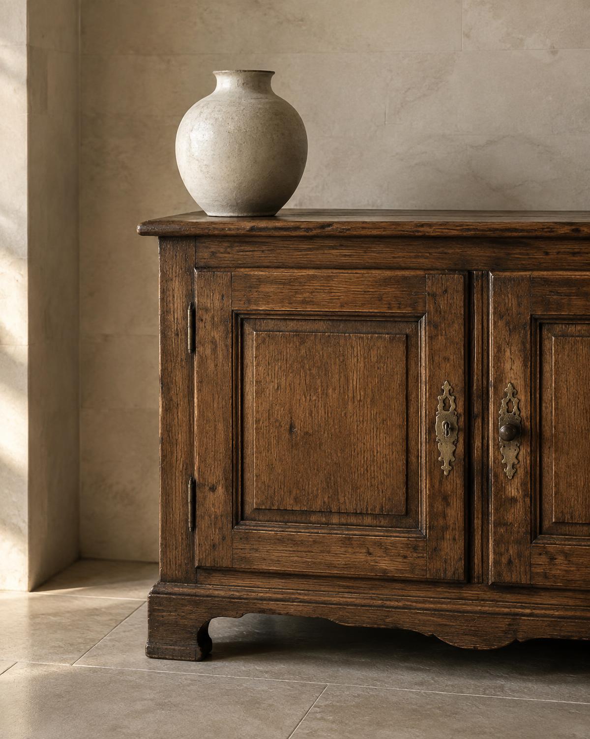 A restored oak cabinet with aged brass hardware against natural stone — Conceptual Design Visualisation.